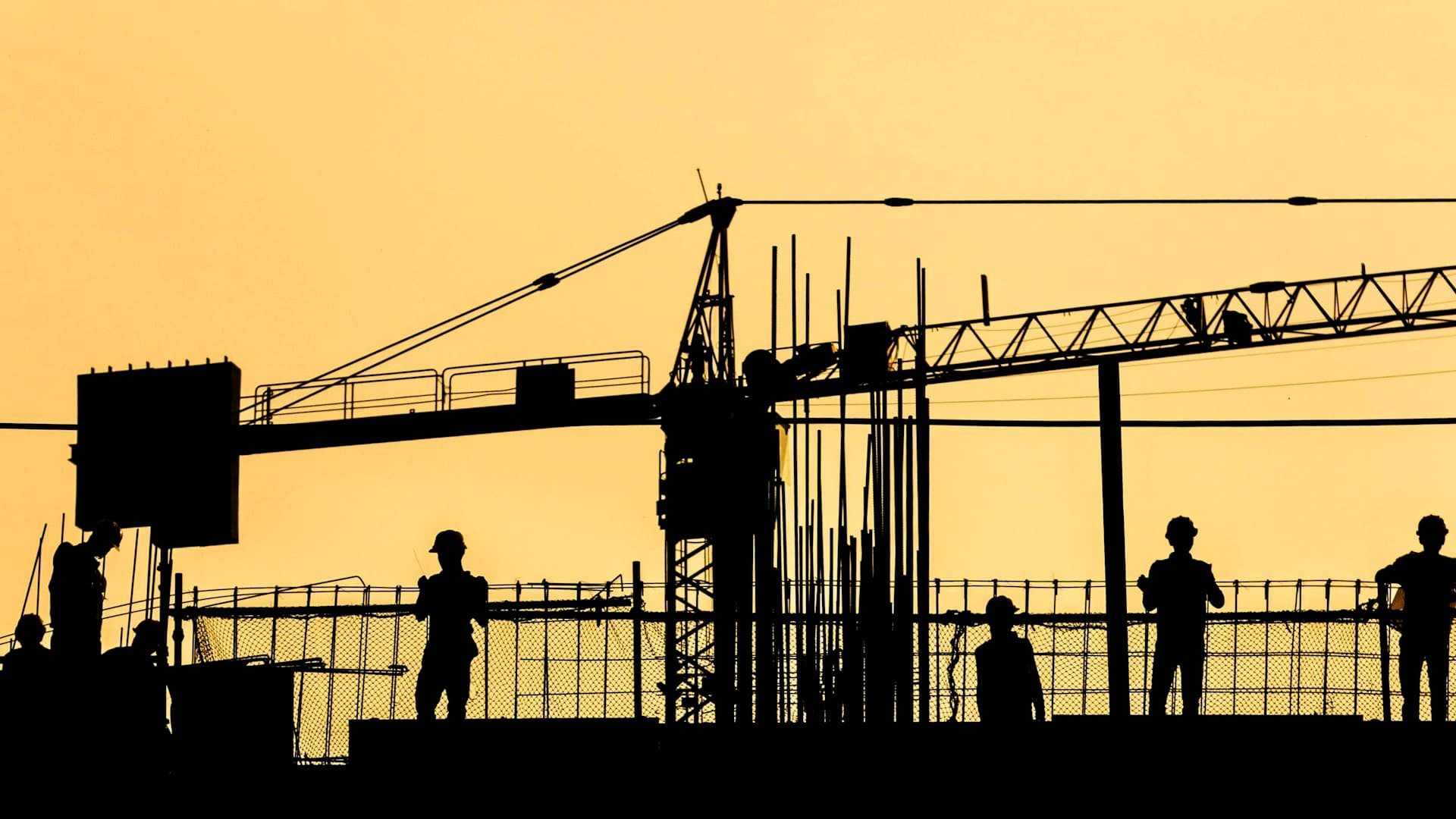 Construction site at sunset with tower crane and site team